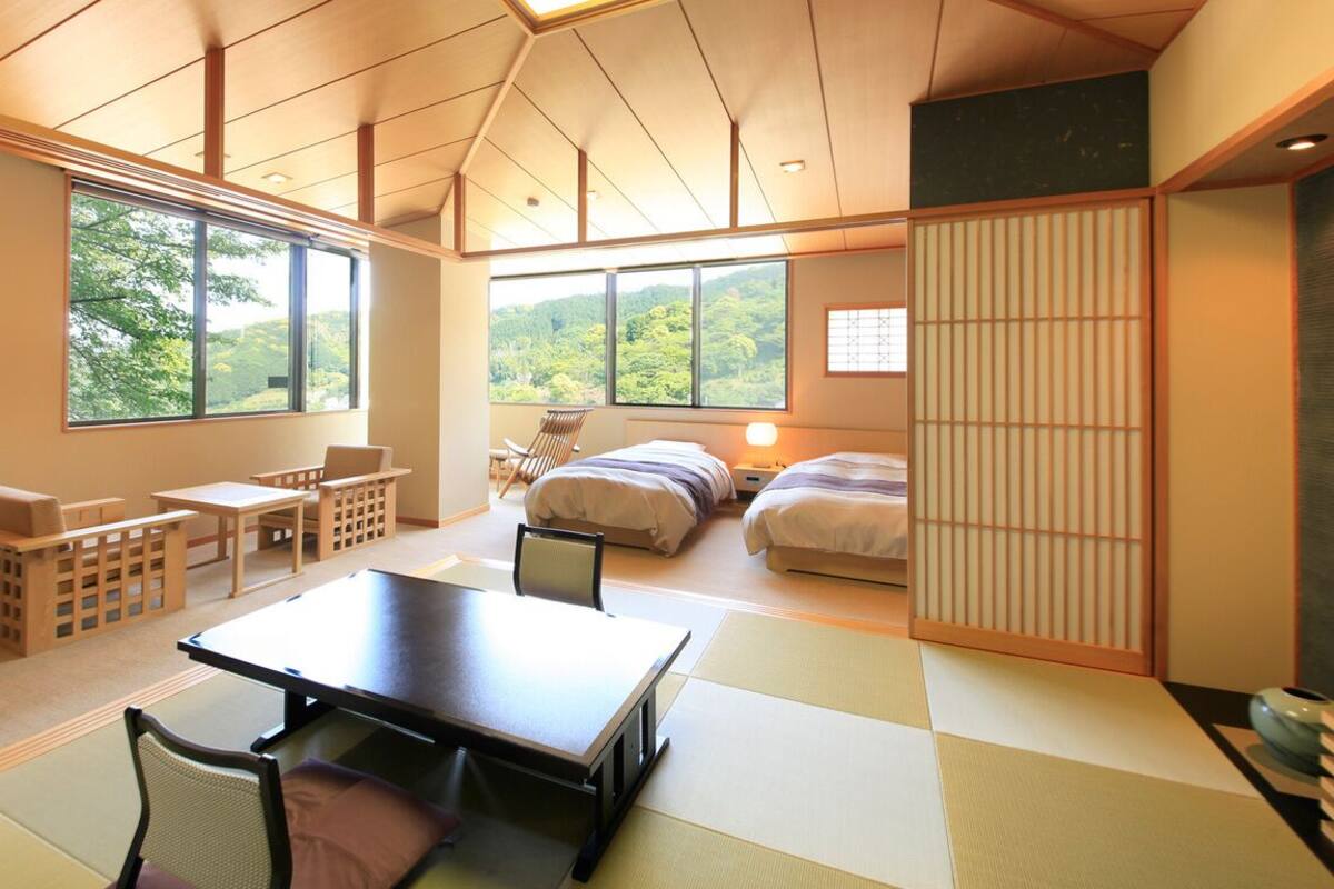 A traditional Japanese-style room with tatami flooring, a low table, and a view of greenery outside.