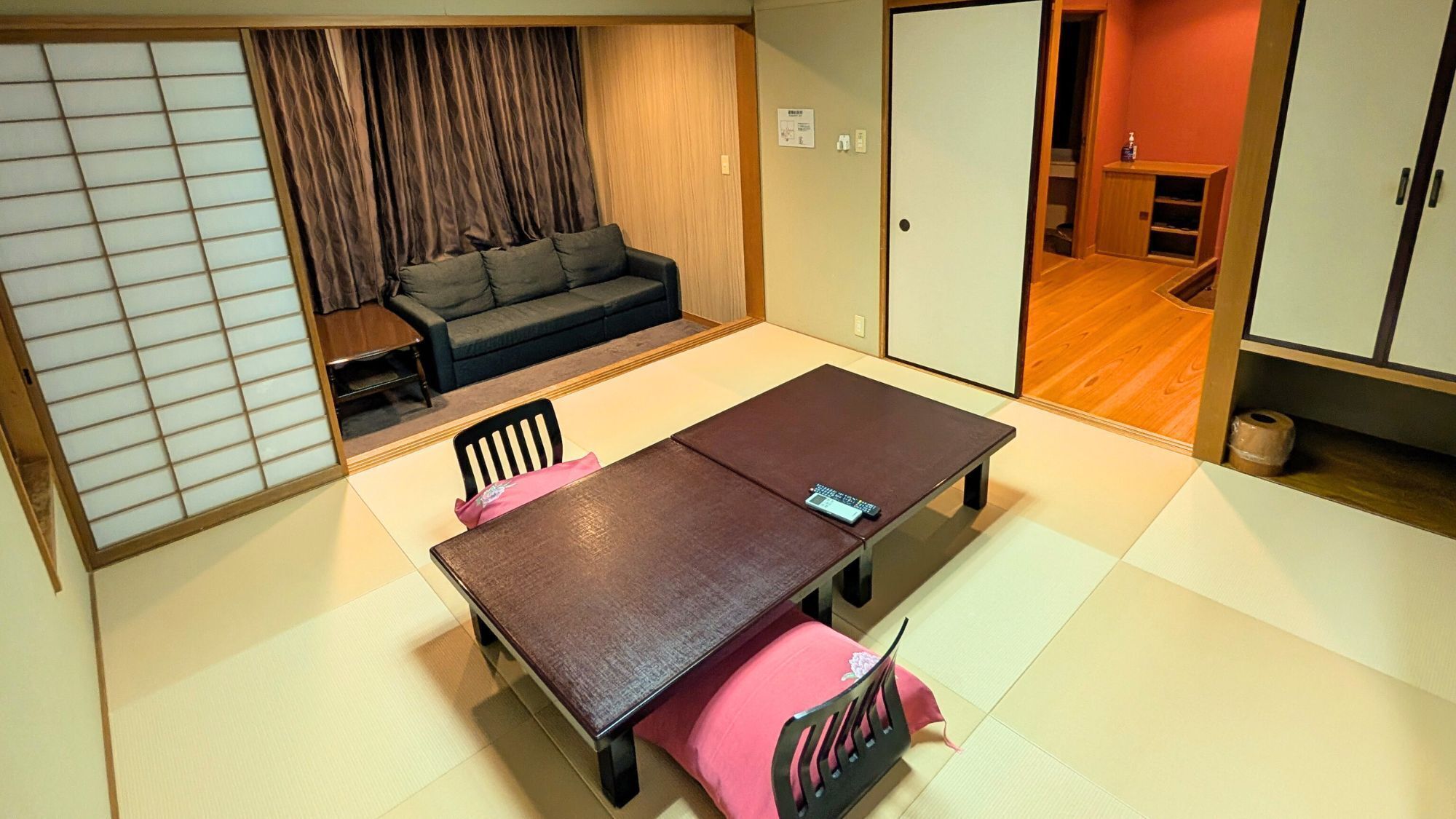 Una tradizionale stanza giapponese con tatami, un tavolino, sedie e un futon.