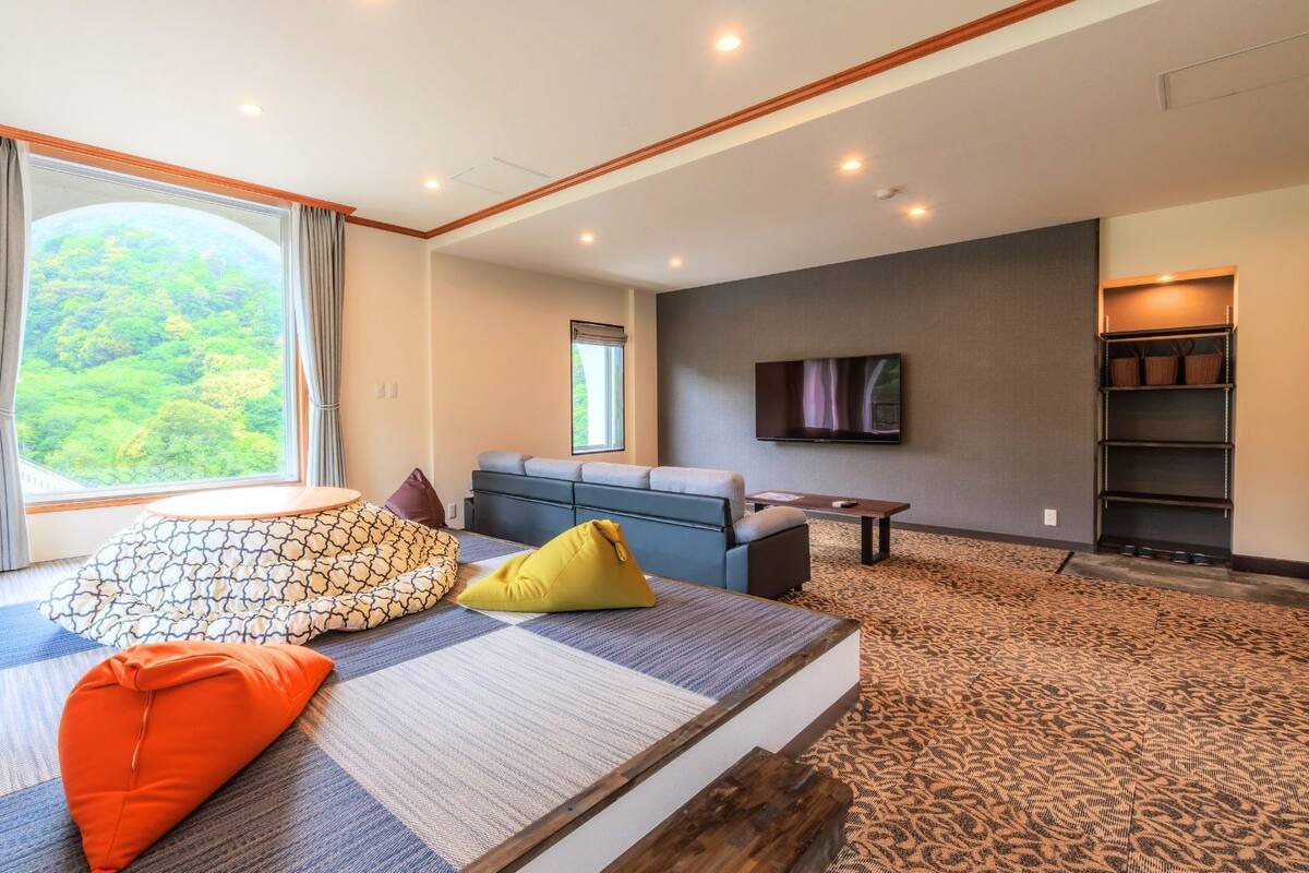 Una sala de estar moderna con un ventanal grande, un televisor de pantalla plana, un sofá y una mesa de centro.