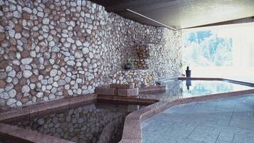 A spa area with a stone wall, a reflecting pool, and a potted plant.