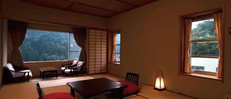 A traditional tatami mat room with a low table, chairs, and a lantern.