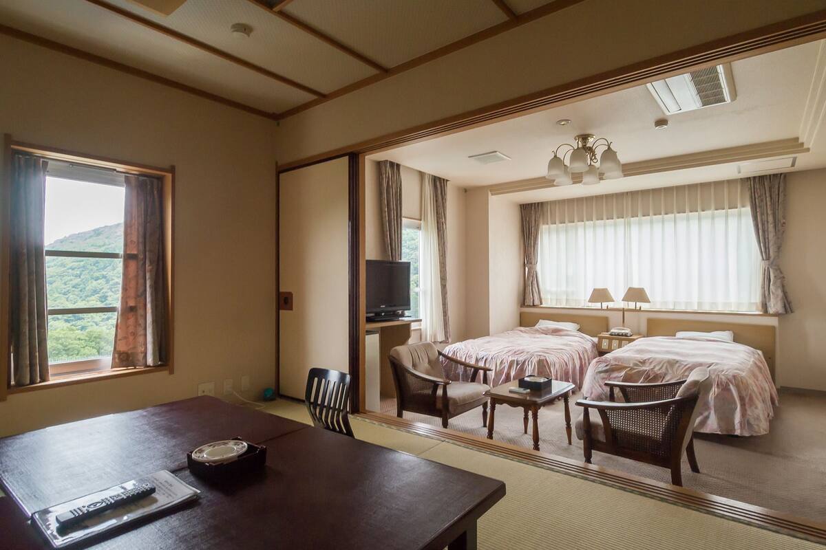 Habitación de hotel con cama, escritorio, silla, televisión y vista a un paisaje montañoso.