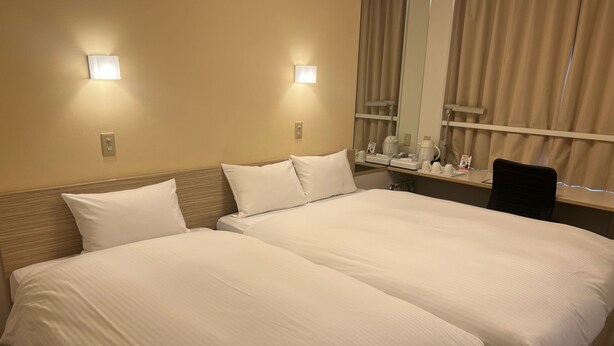 A hotel room with two beds, a desk with a chair, a mirror, and two wall-mounted lights. - Smile Hotel Shirakawa (Nishigo)