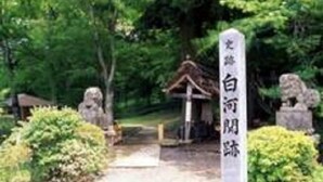 A traditional Japanese torii gate leading to a shrine, surrounded by lush greenery and stone lanterns. - Smile Hotel Shirakawa (Nishigo)