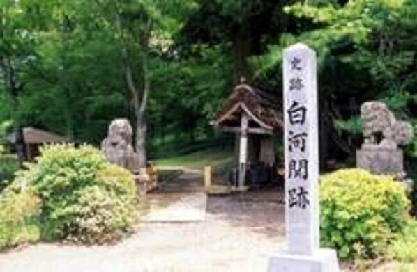 A traditional Japanese torii gate leading to a shrine, surrounded by lush greenery and stone lanterns. - Smile Hotel Shirakawa (Nishigo)