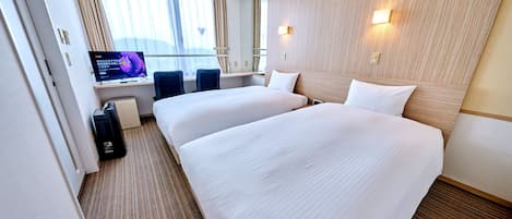 Una habitación de hotel con dos camas, un escritorio, una televisión y una ventana con cortinas.