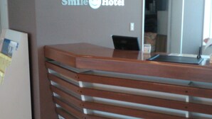 A reception desk with a 'Smile Hotel' sign, a mirror, and a small table. - Smile Hotel Shirakawa (Nishigo)