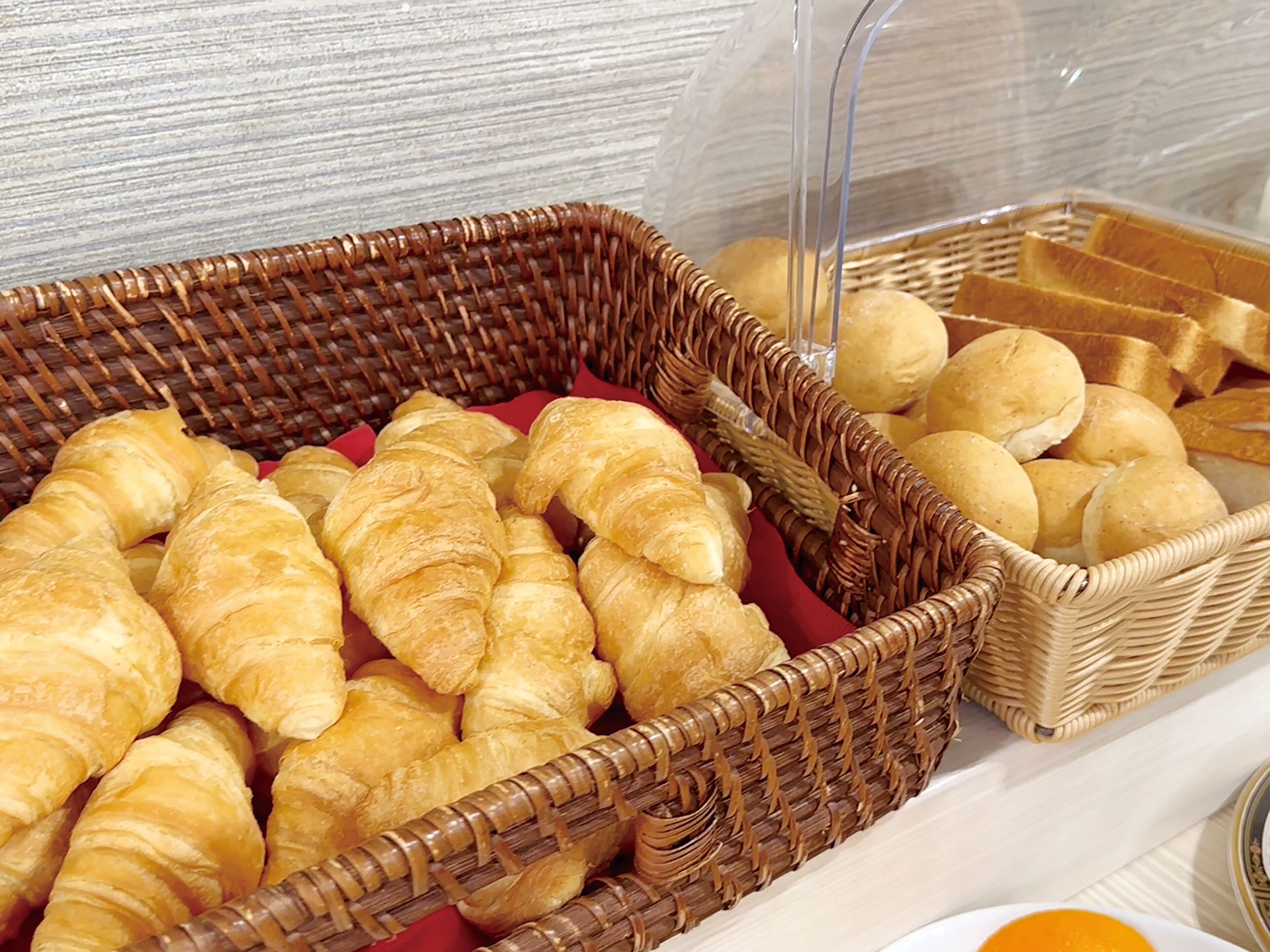 A display of baked goods including croissants and bread rolls in wicker baskets.