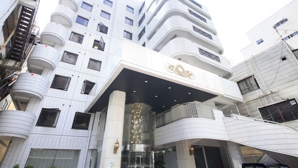 A modern hotel with a curved facade, multiple balconies, and a prominent entrance with a decorative sign. - Hotel Green Pacific (Sendai)