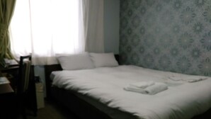 A single bed with white linens, a chair, and a desk in a room with patterned wallpaper. - Hotel Green Pacific (Sendai)