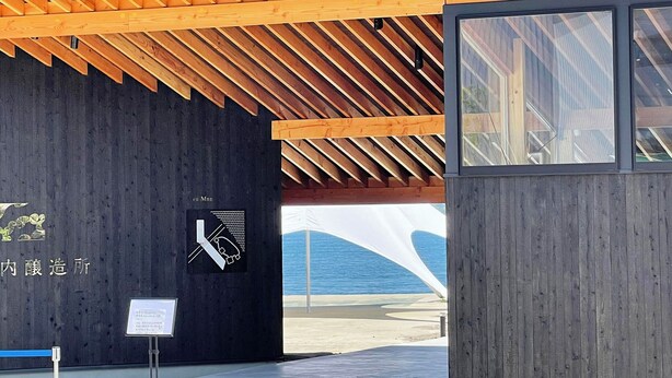 A modern building with a wooden ceiling and a view of the sea.