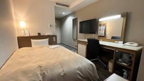 A hotel room with a bed, desk, chair, and a television.