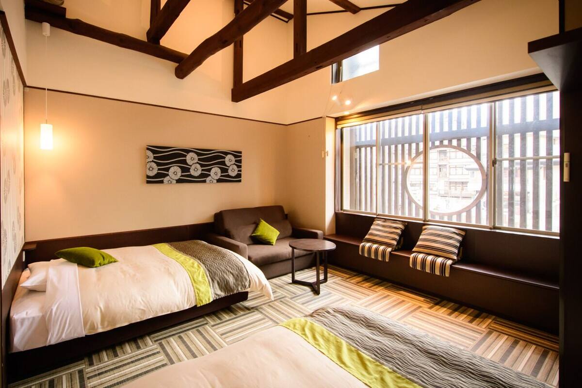 A hotel room with a bed, a sofa, a small table, and a window with a view.