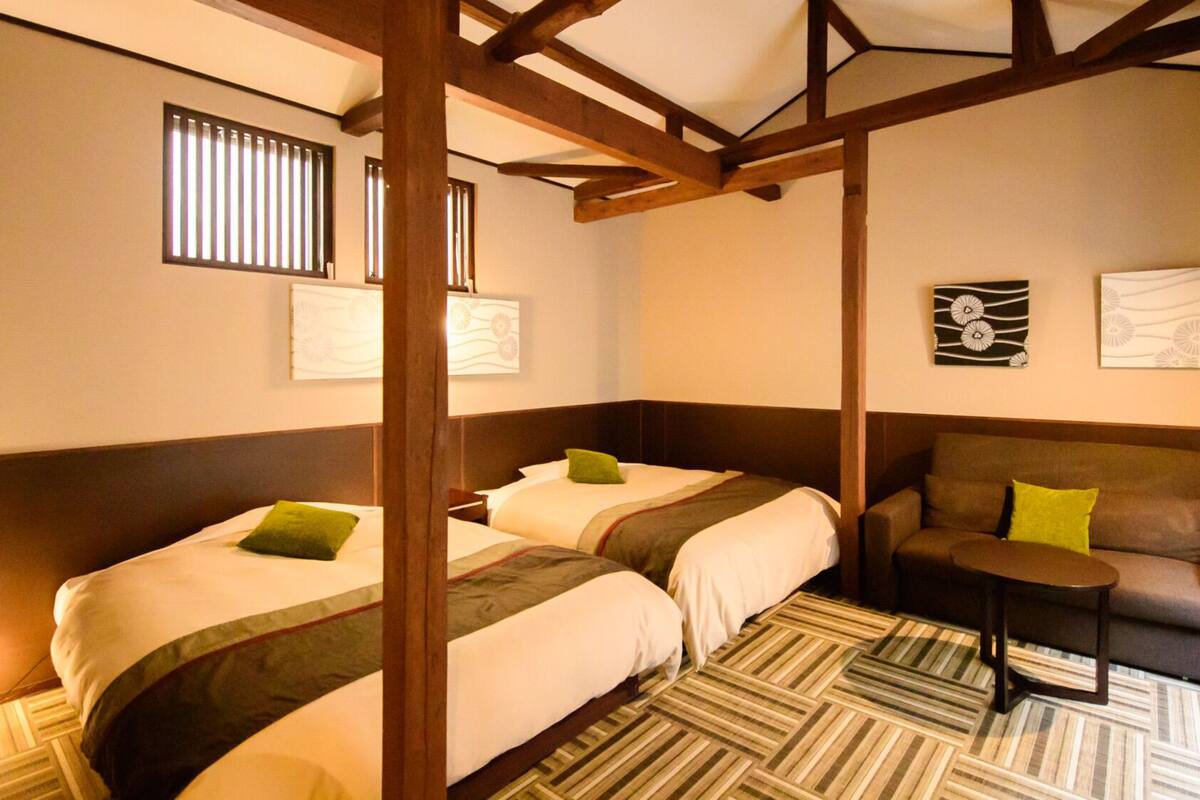A hotel room with two beds, a sofa, a small table, and artwork on the walls.