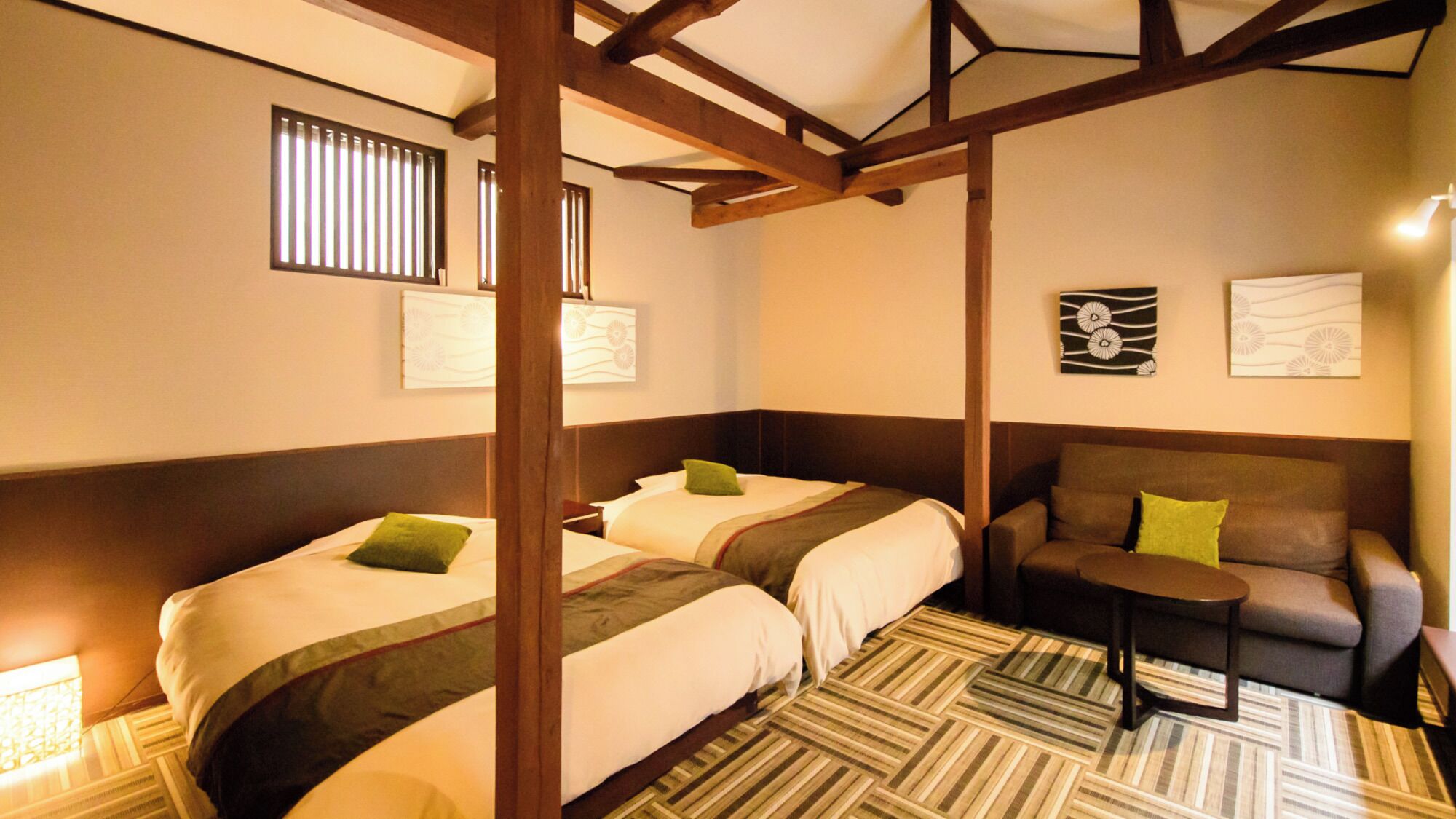 Ein Hotelzimmer mit zwei Betten, einem Sofa, einem kleinen Tisch und Bildern an den Wänden.
