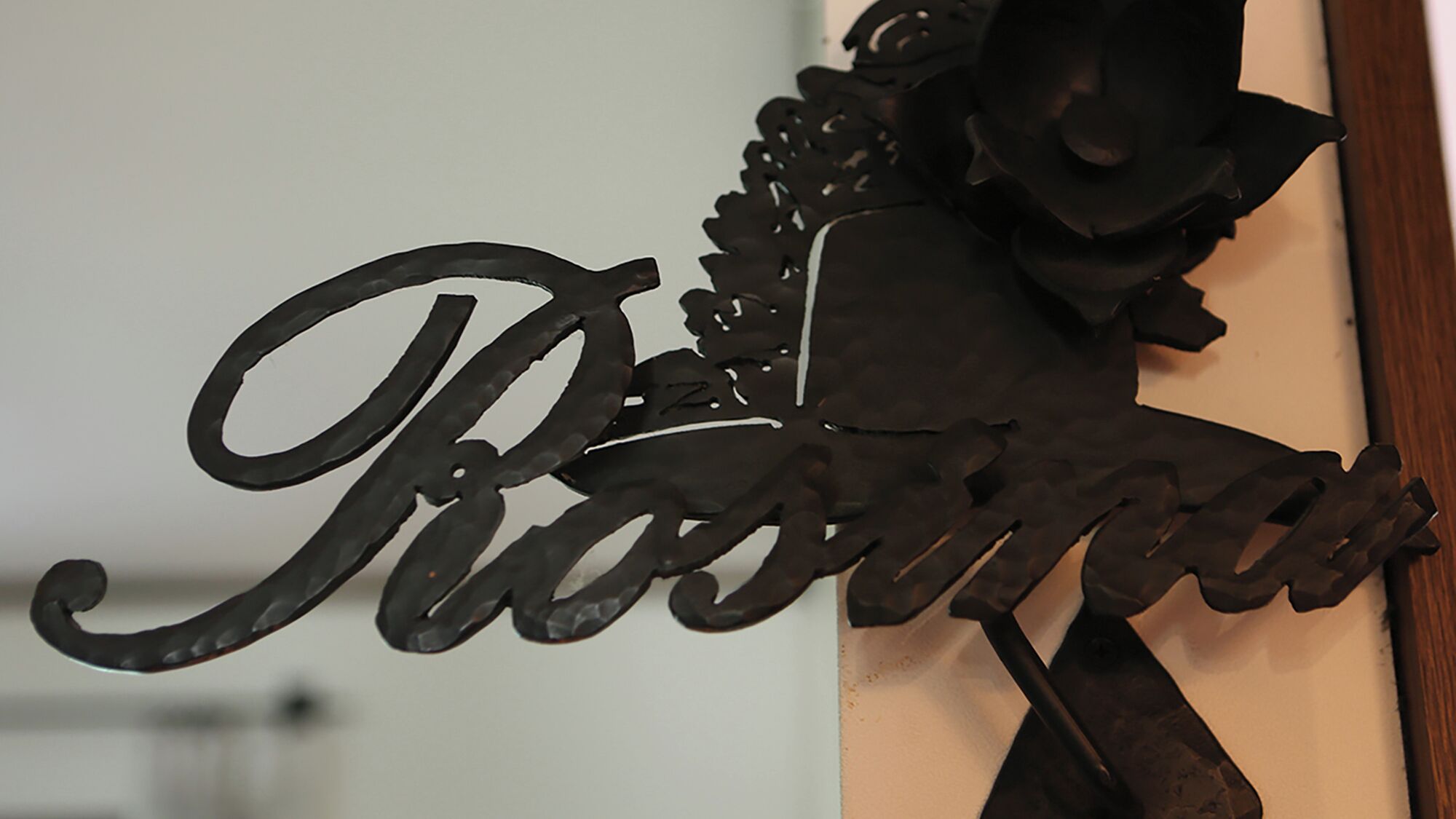 A decorative metal sign with the name 'Rosina' in cursive lettering.