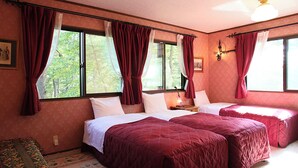 Une chambre avec deux lits, des rideaux rouges, un lustre et une fenêtre donnant sur des arbres.