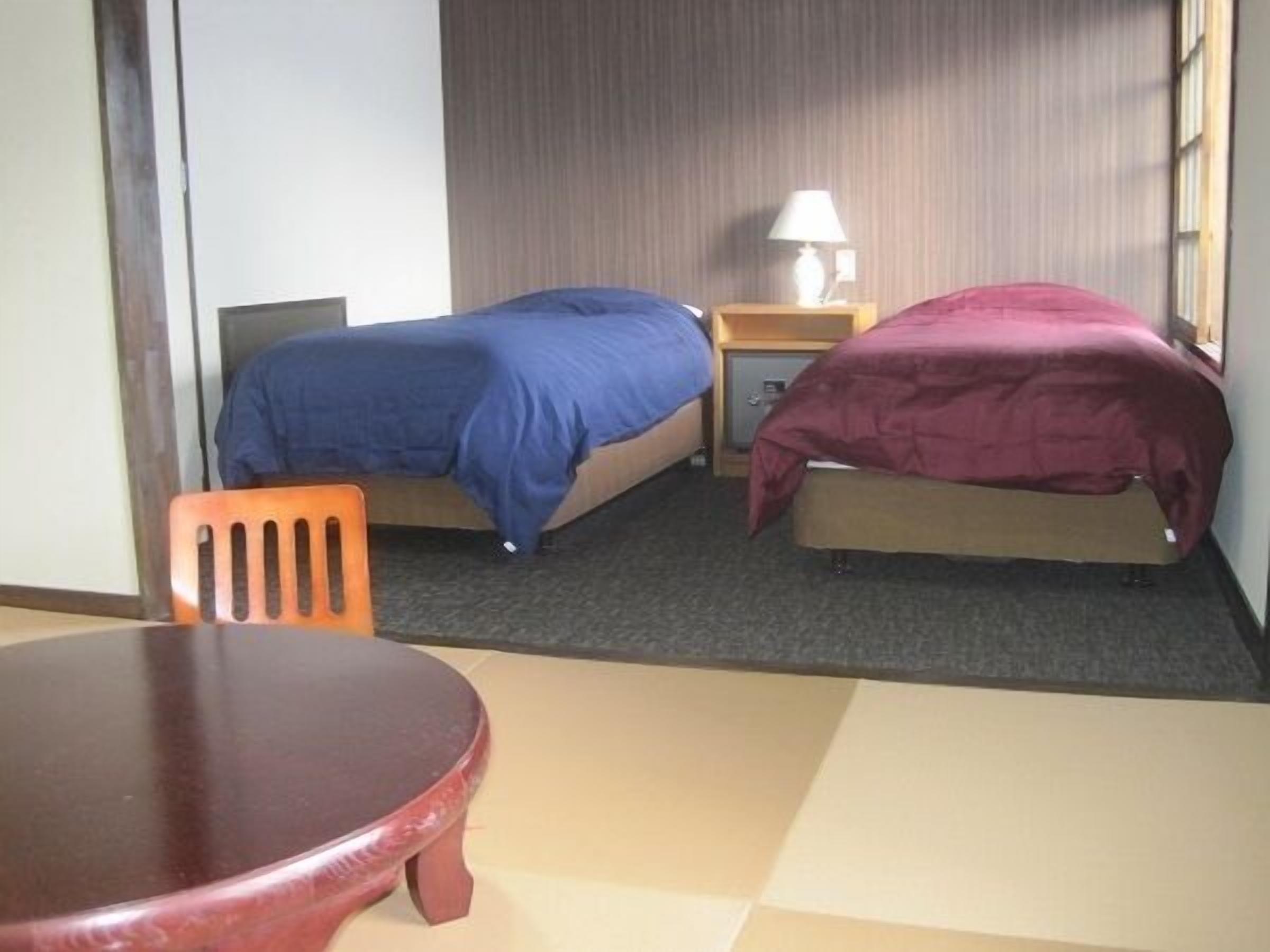 Habitación de hotel con dos camas, una mesita y una silla.