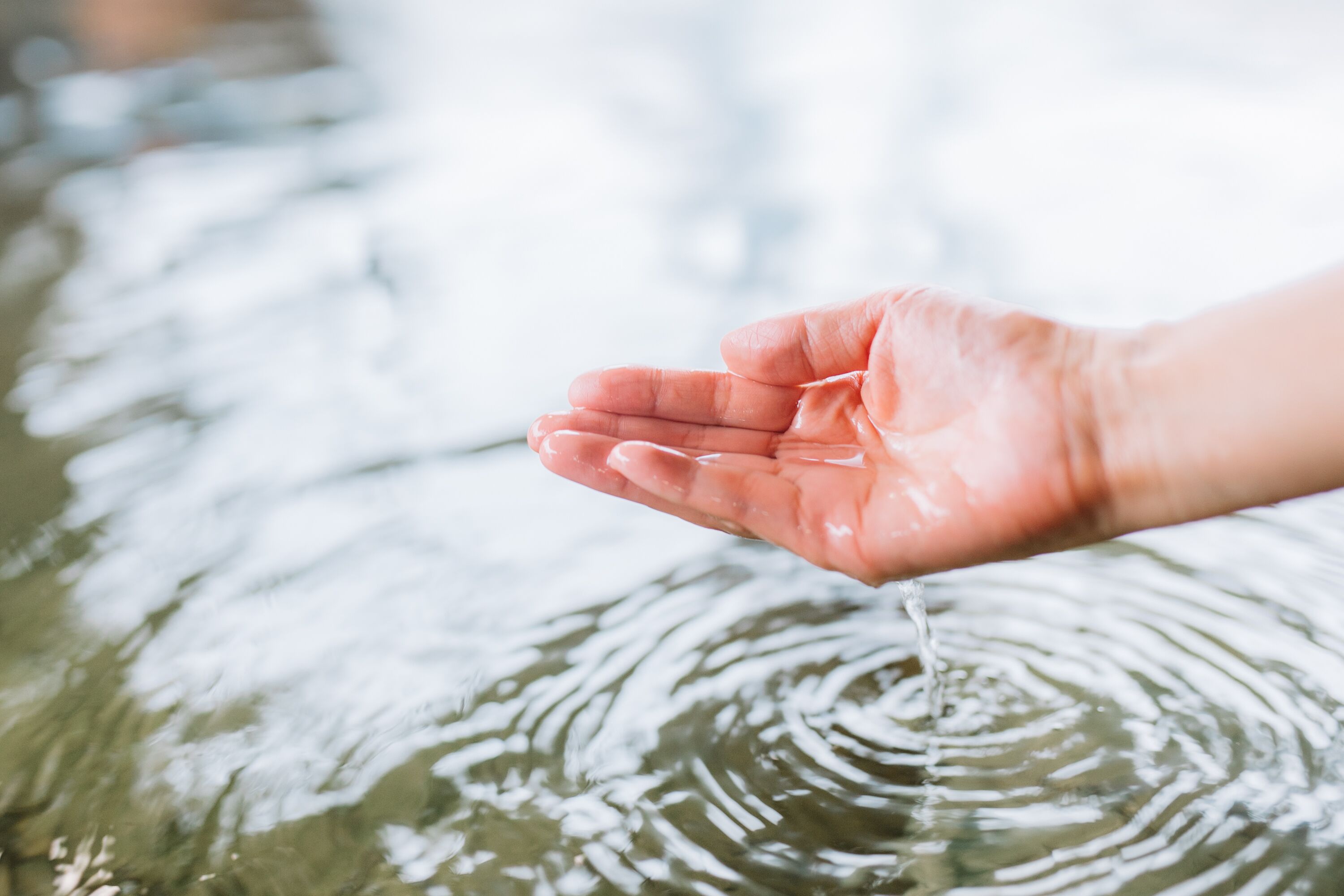 Een hand die in het water reikt.