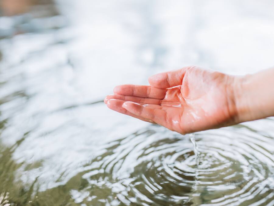 Een hand die in het water reikt.
