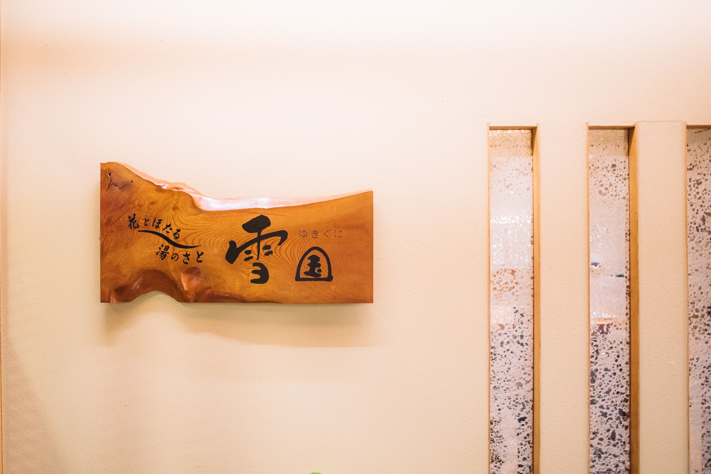 Un mur orné d’une plaque en bois sur laquelle figurent des caractères japonais et d’un panneau métallique au motif moucheté.
