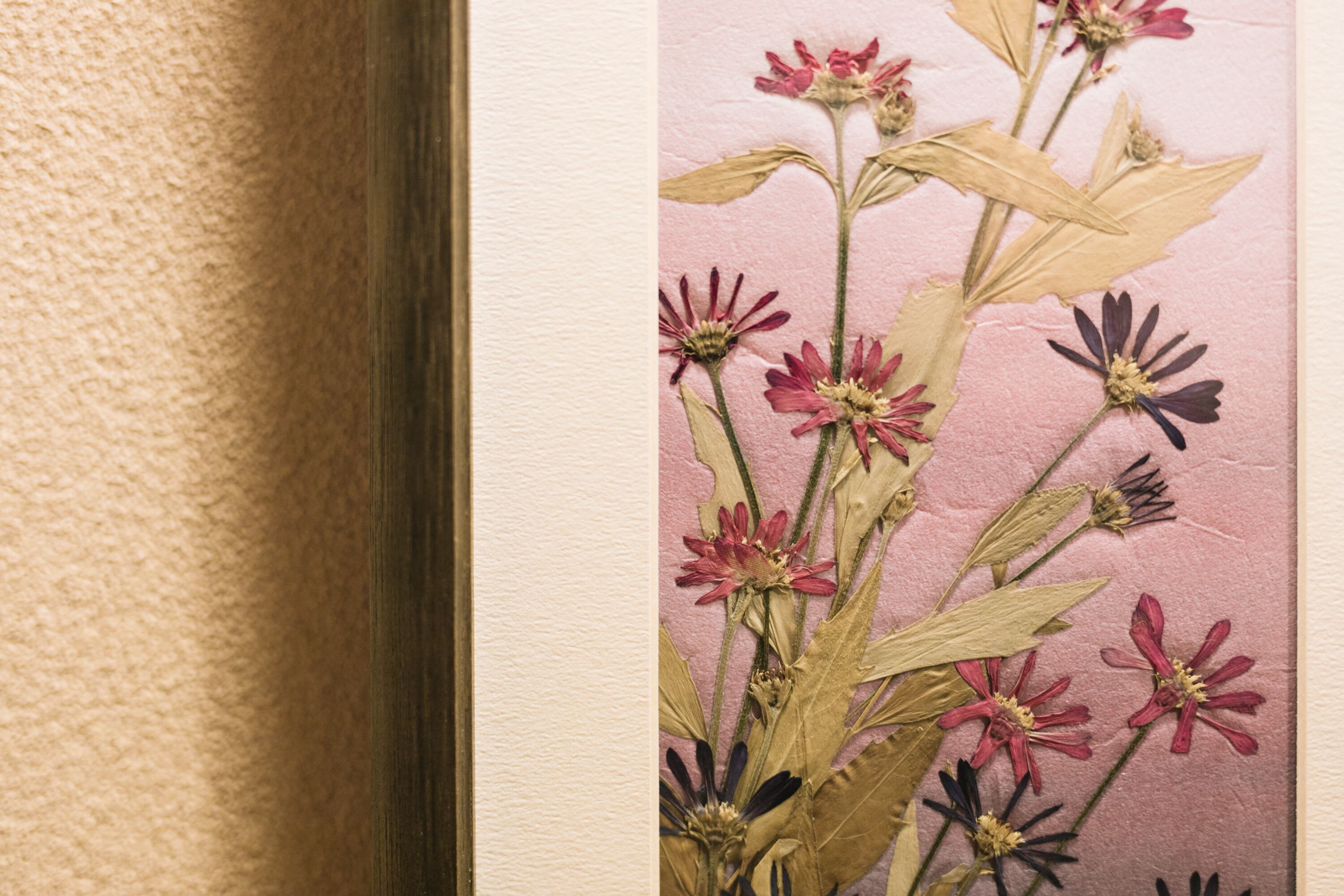 Un muro dalla superficie decorativa con fiori e foglie essiccate.