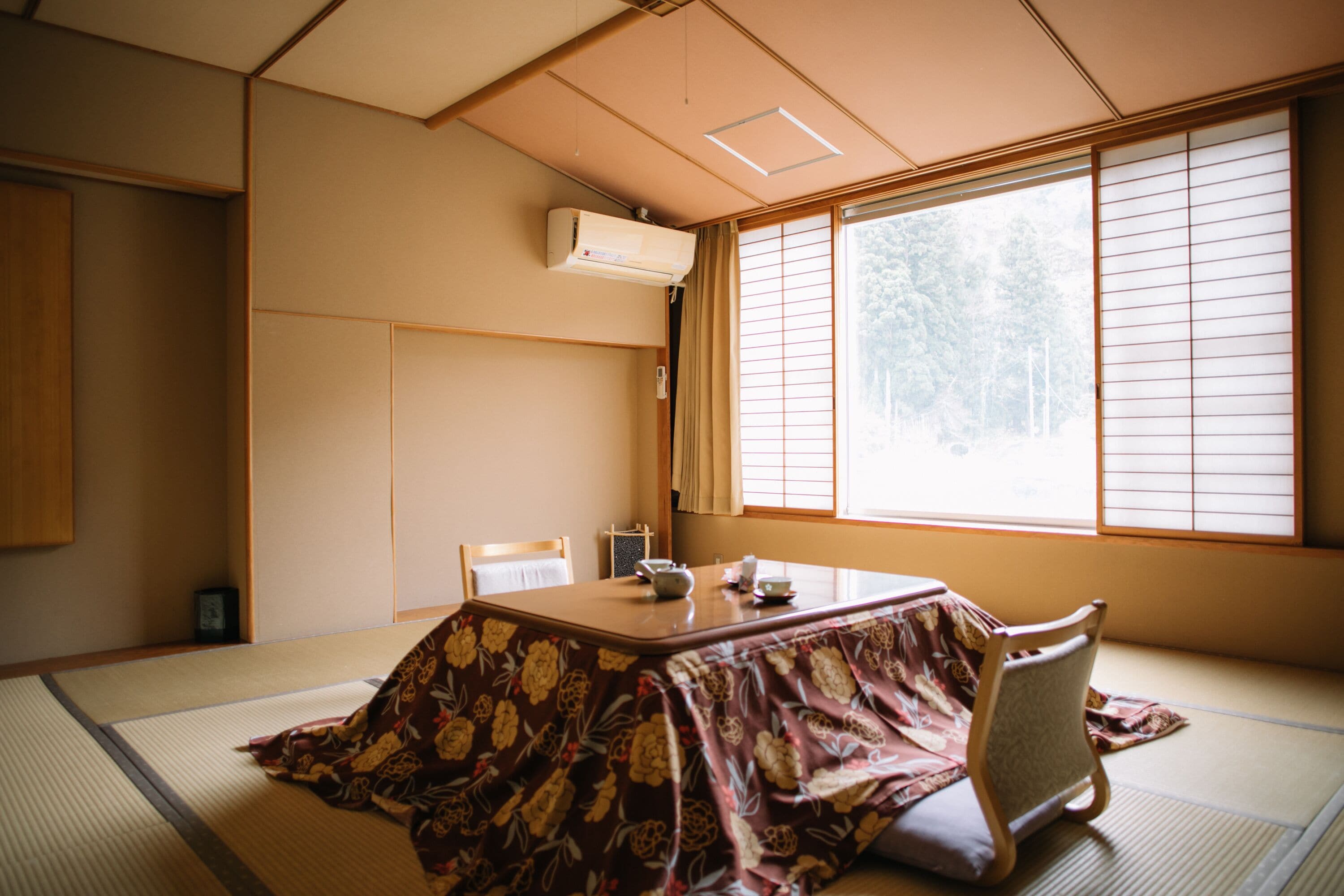 Une pièce de style japonais traditionnel, avec un sol recouvert de tatamis, une table basse et une chaise.