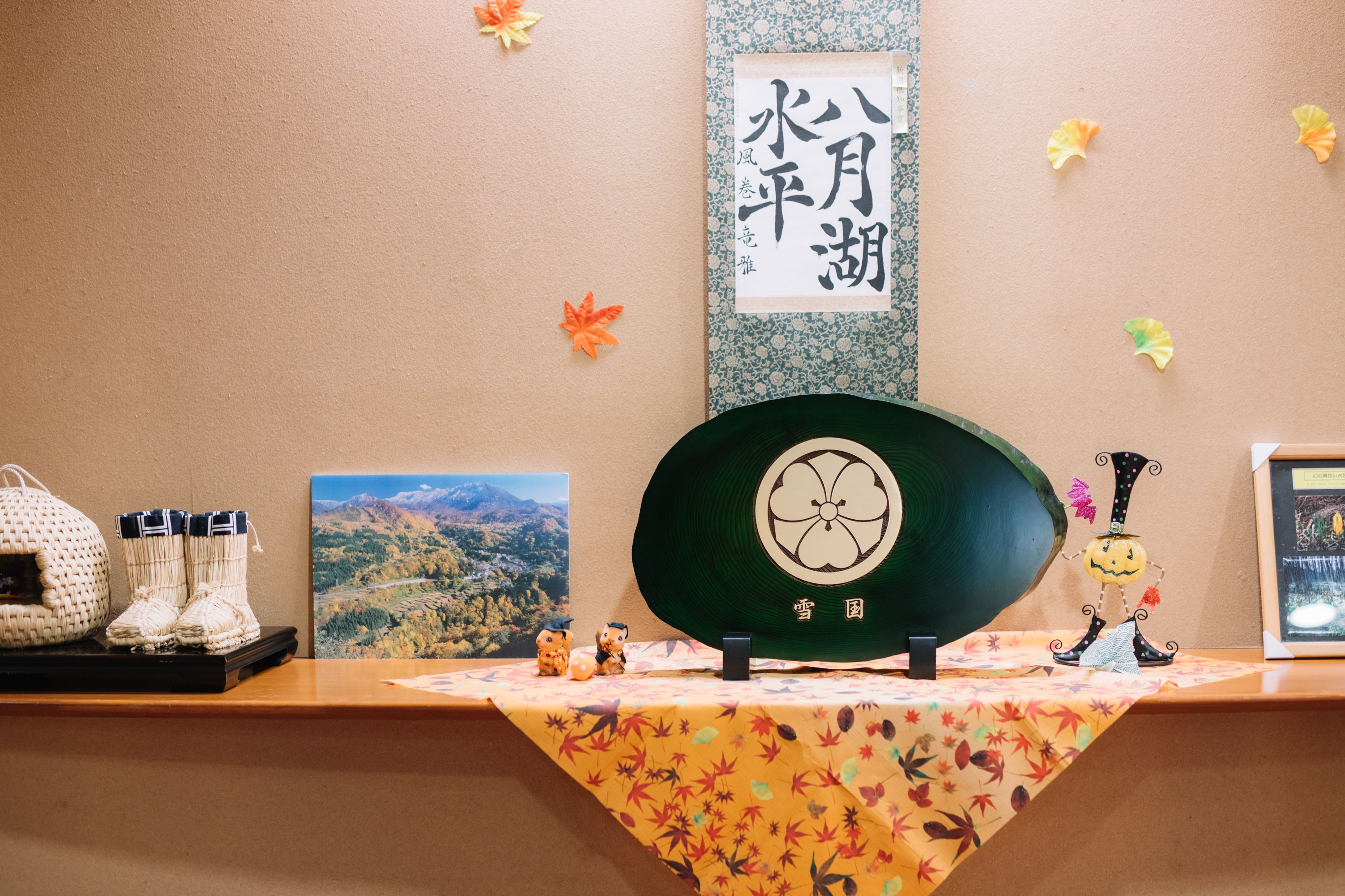 Ein Empfangsschalter mit dekorativer Tischdecke, einem gerahmten Bild, einem Dekorationsgegenstand und einem Schild mit japanischen Schriftzeichen.