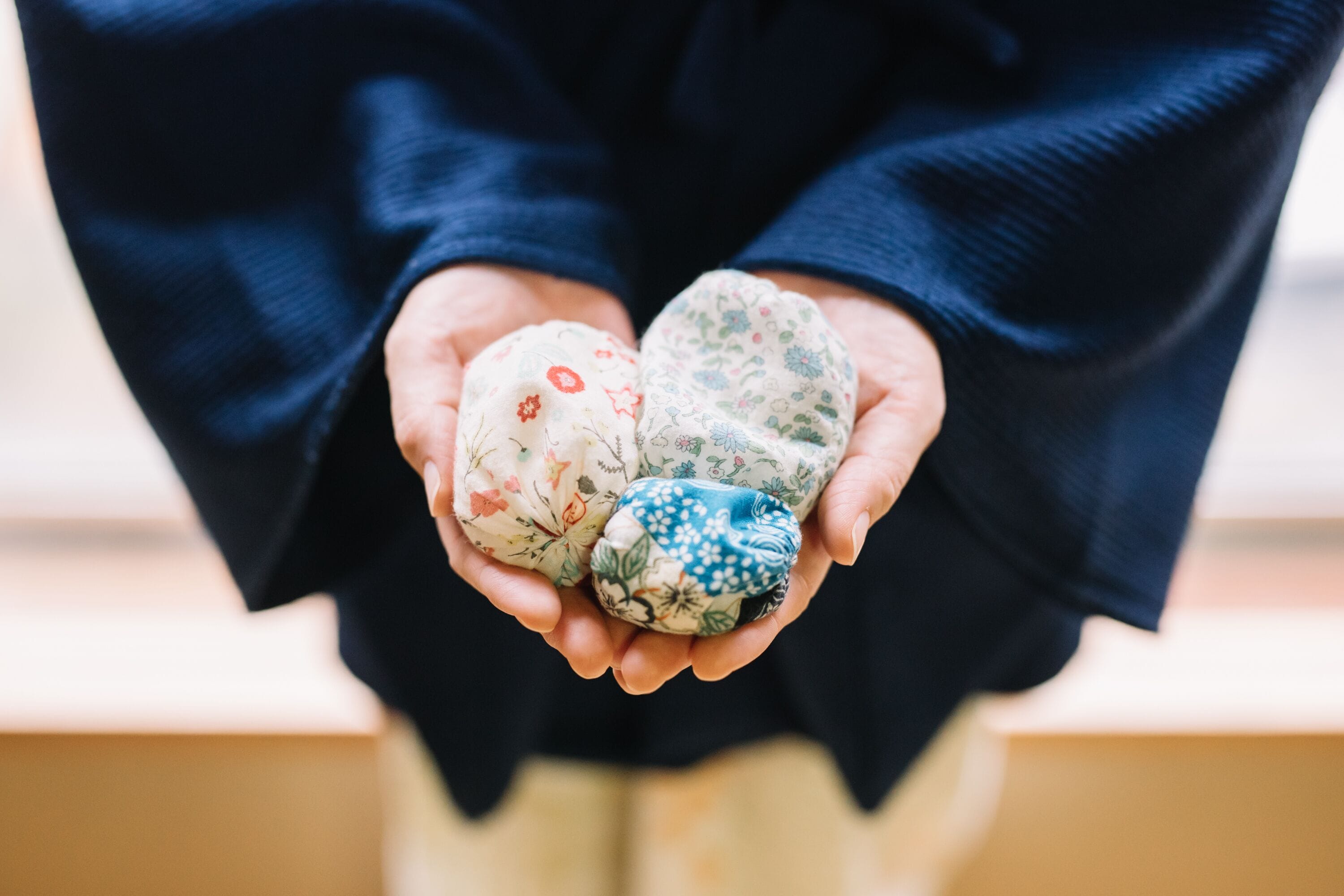 A person holding three patterned fabric items.