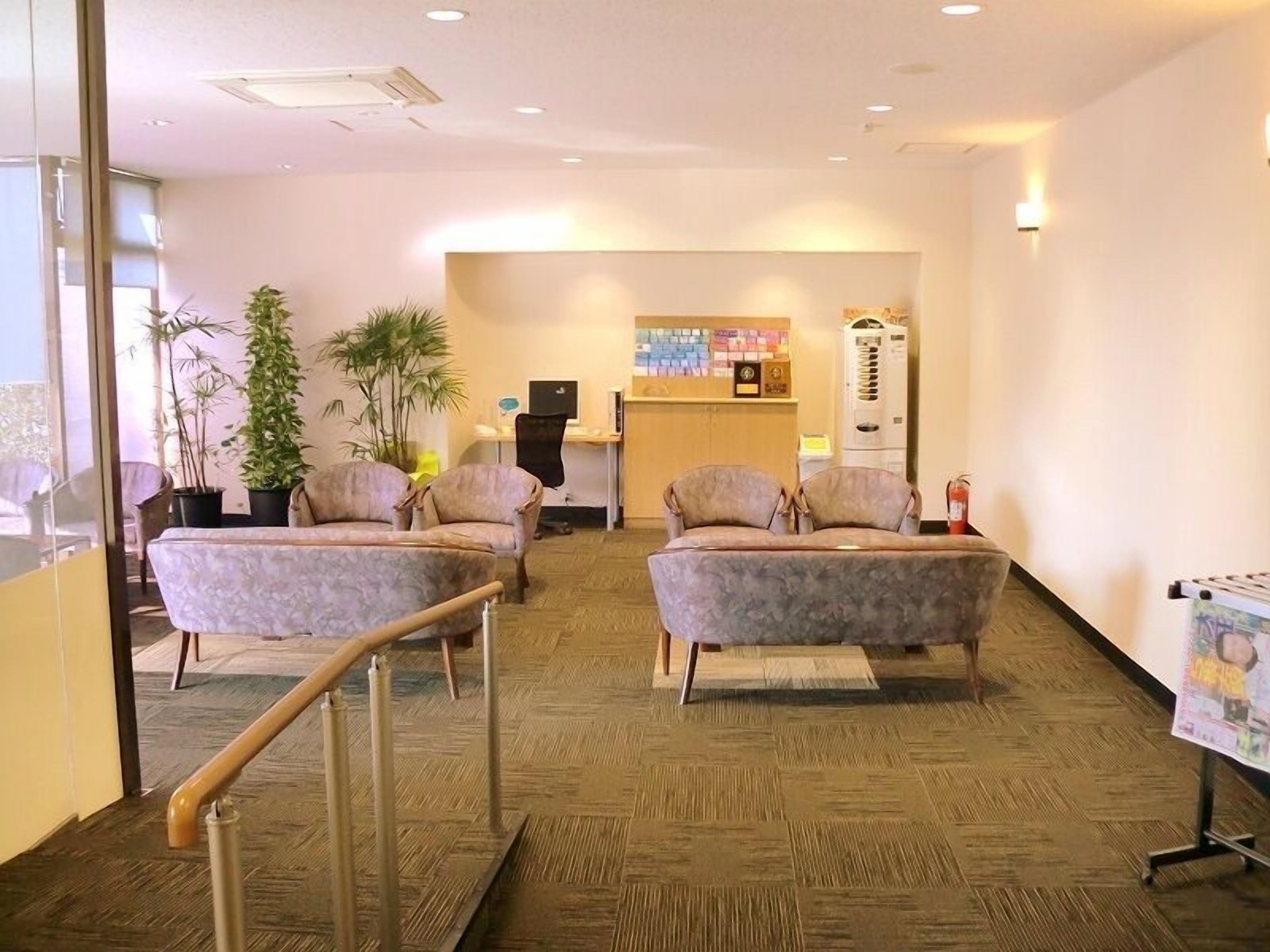 A reception area with two sofas, a reception desk, a vending machine, and a wall-mounted information board.