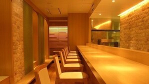 A long bar area with multiple seating arrangements and a stone wall. - Hotel Sunroute Sukagawa (Sukagawa)