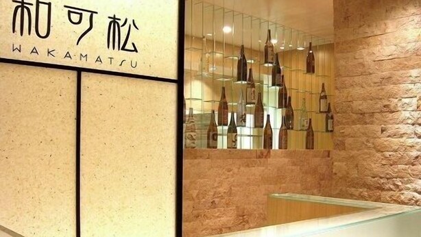 A reception area with a stone wall and a display of bottles. - Hotel Sunroute Sukagawa (Sukagawa)
