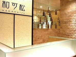 A reception area with a stone wall and a display of bottles. - Hotel Sunroute Sukagawa (Sukagawa)