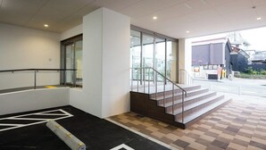 A modern building entrance with a staircase, a glass door, and a tiled floor. - Hotel Sunroute Sukagawa (Sukagawa)