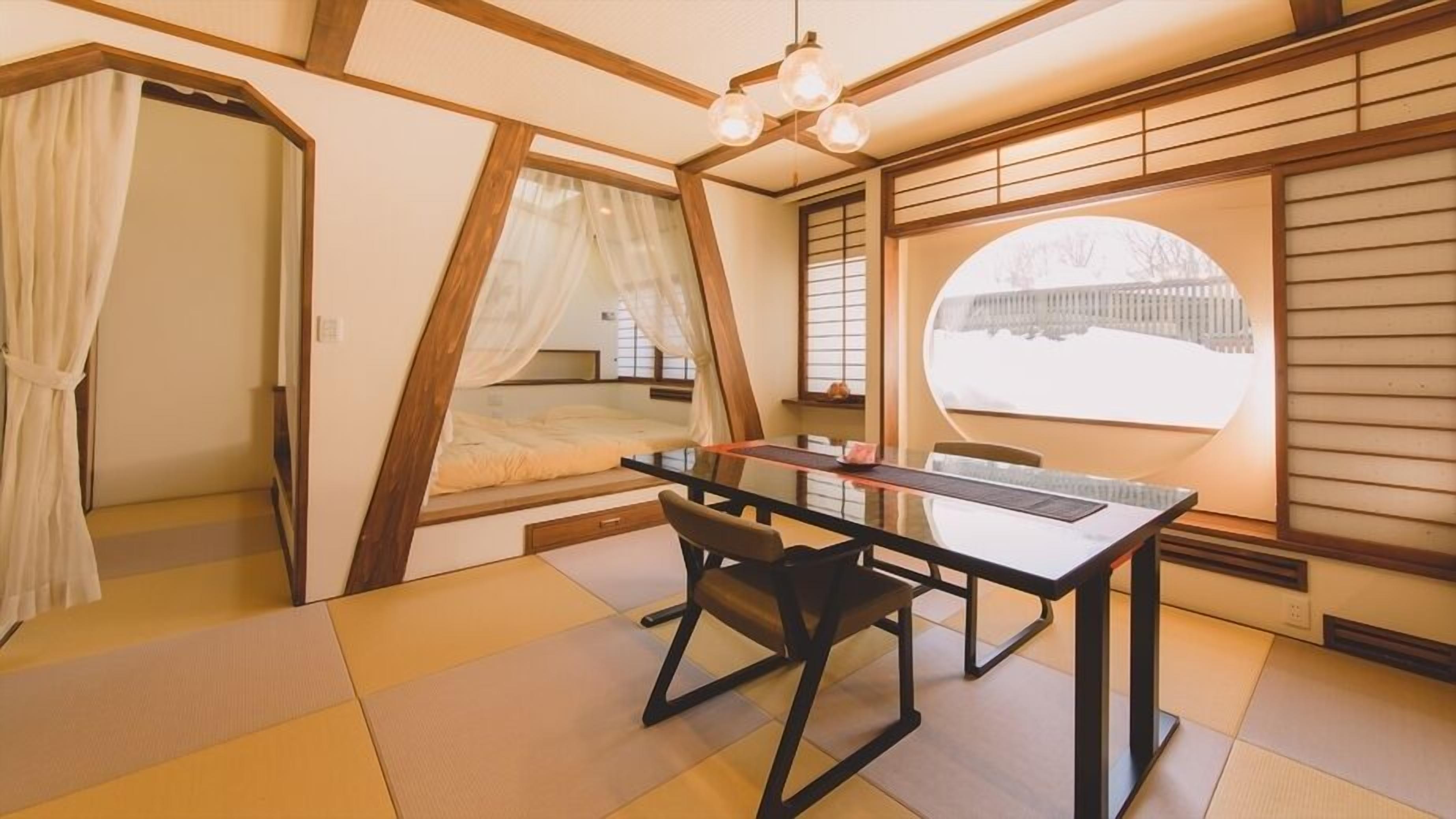 Ein Zimmer mit einem Bett, einem Tisch und einem Fenster mit Aussicht.