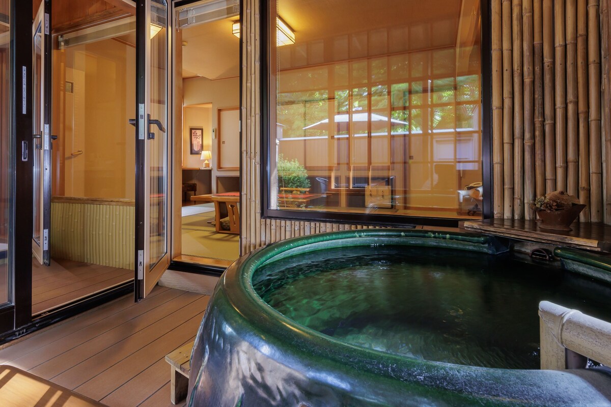 A hot tub on a wooden deck with glass doors leading to a room.