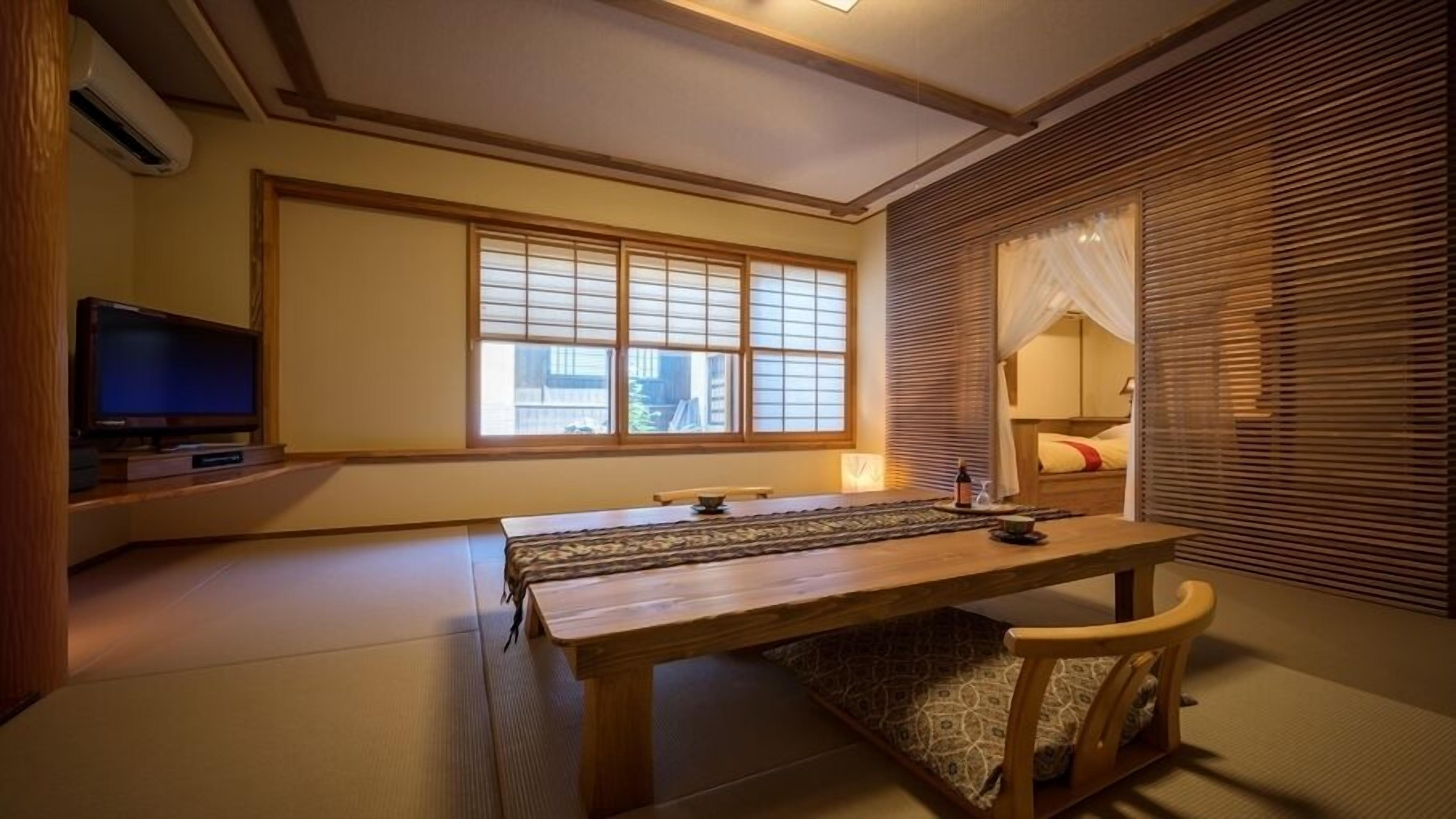 Ein traditioneller japanischer Raum mit Tatami-Böden, einem niedrigen Tisch, einem Fernseher und gleitenden Shoji-Schiebetüren.