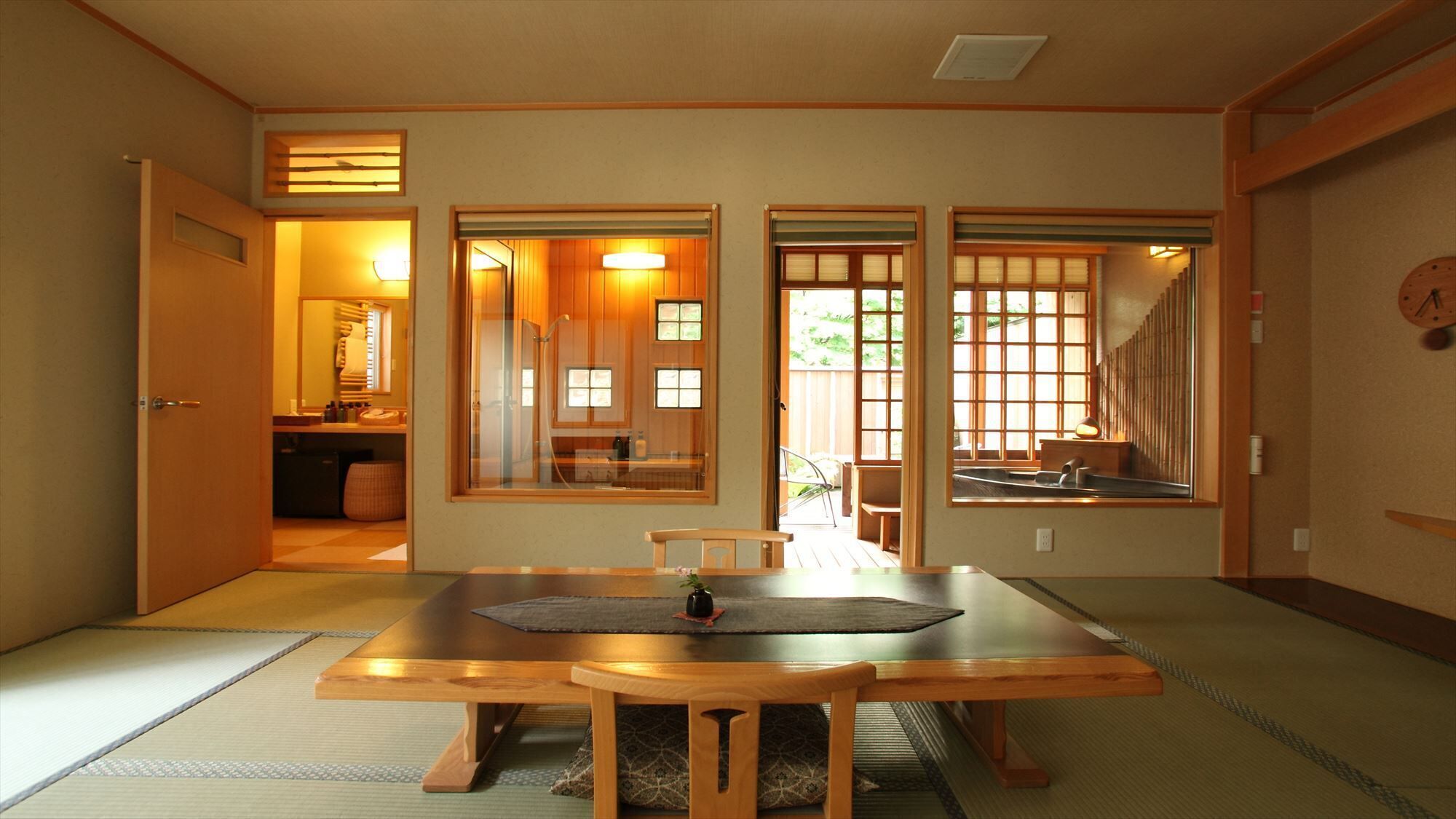 Habitació tradicional japonesa amb sòls de tatami, una taula baixa amb coixins, portes corredisses i vista a l'exterior.
