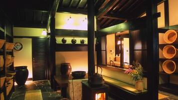 A traditional interior with a stone floor, a wood-burning stove, and shelves with pottery.