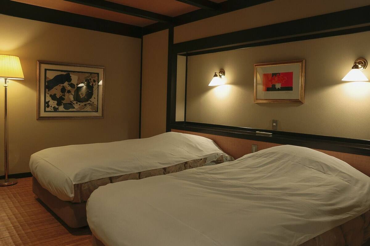 Ein Hotelzimmer mit zwei Betten, einer Stehlampe und zwei Wandleuchten.