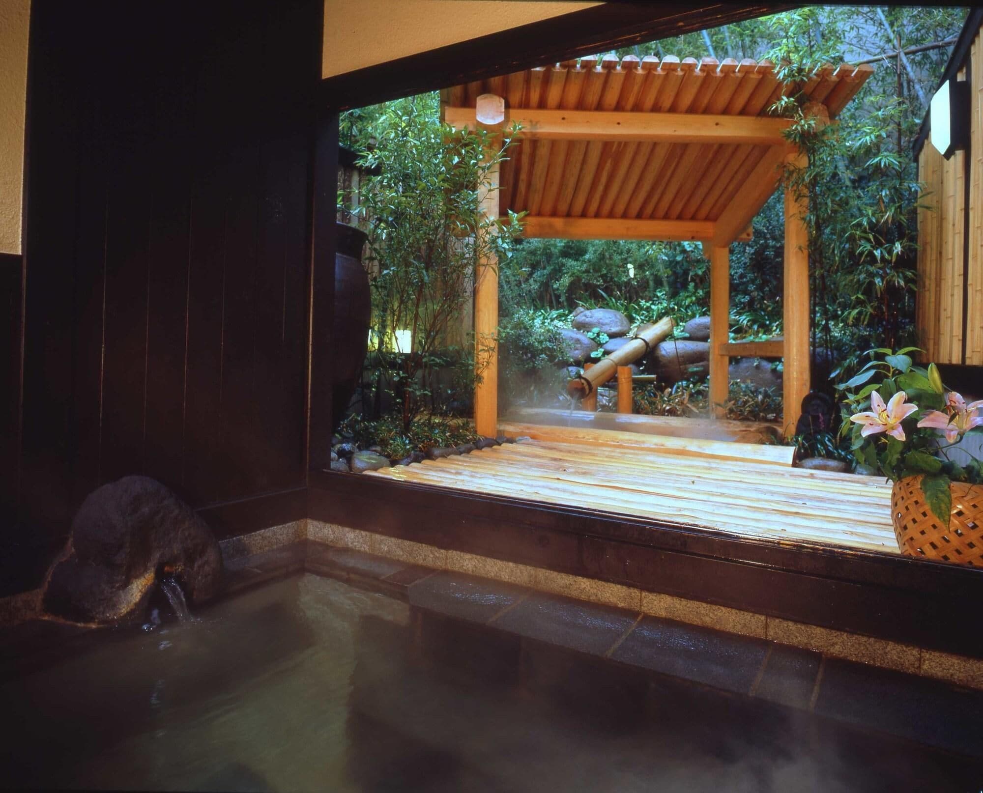 Een traditioneel Japans onsen met een houten constructie, een stenen bad en weelderige begroeiing.