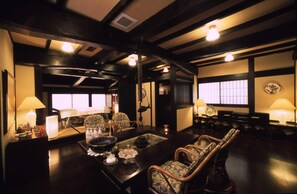 A traditional Japanese-style room with tatami flooring, low tables, and chairs. There are sliding doors, a fireplace, and a large window. - Hana No Omotenashi Nanraku (Minamiizu)