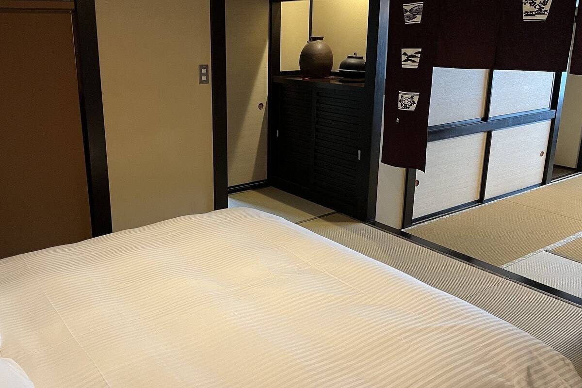 Ein Hotelzimmer mit einem Bett, einem Schminktisch und einer traditionellen japanischen Schiebetür.