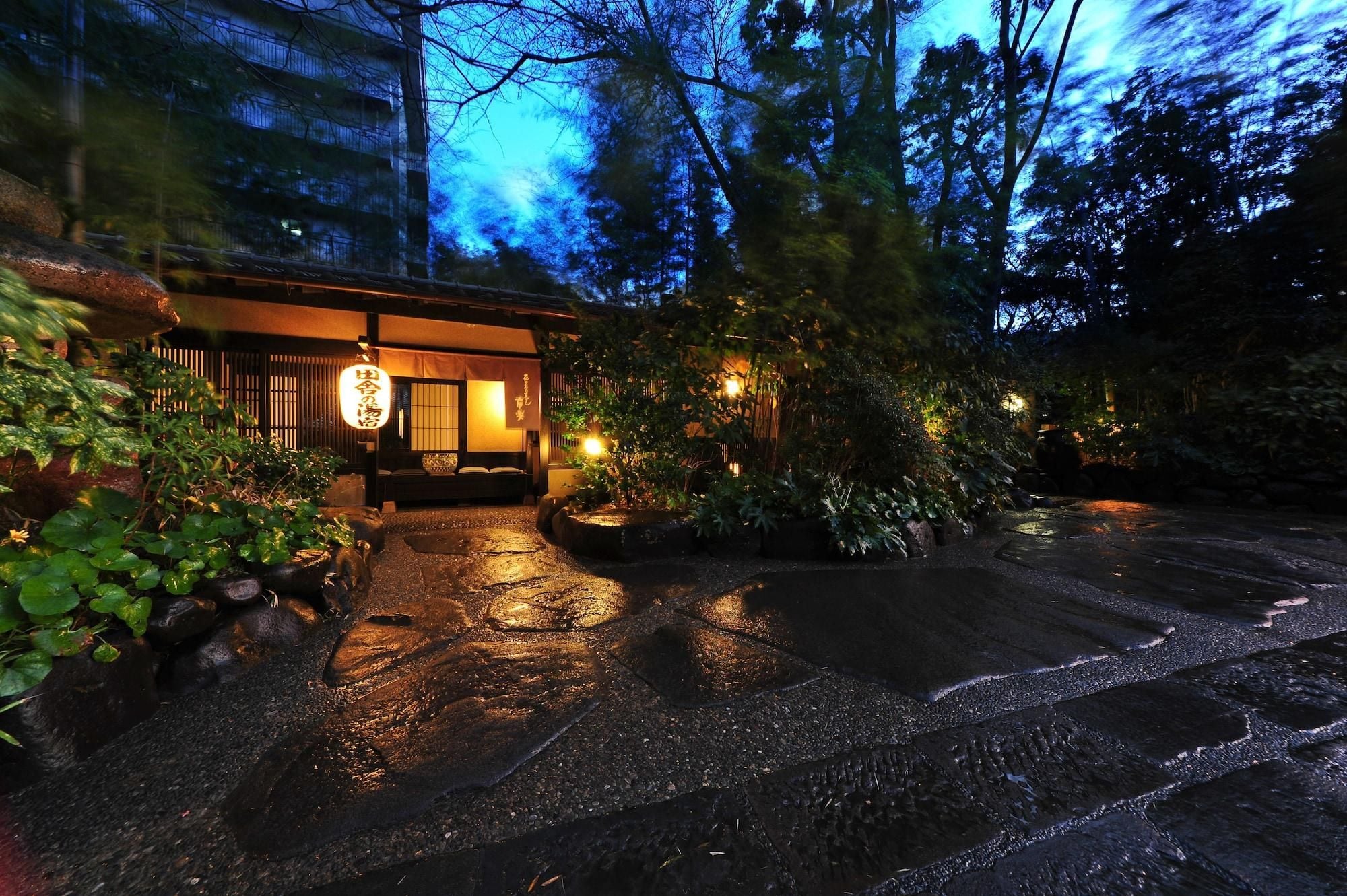 A traditional Japanese building with a wooden exterior, a stone pathway leading to the entrance, and a sign with Japanese characters.