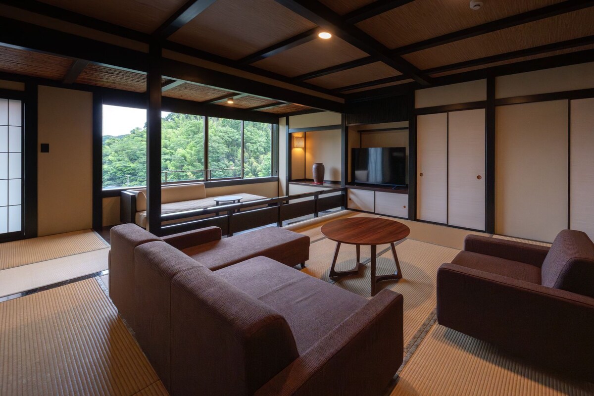Ein traditioneller japanischer Raum mit Tatami-Böden, einem niedrigen Tisch und Sitzgelegenheiten.