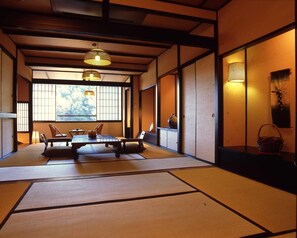 A traditional Japanese room with tatami flooring, a low table with cushions, and sliding doors. - Hana No Omotenashi Nanraku (Minamiizu)