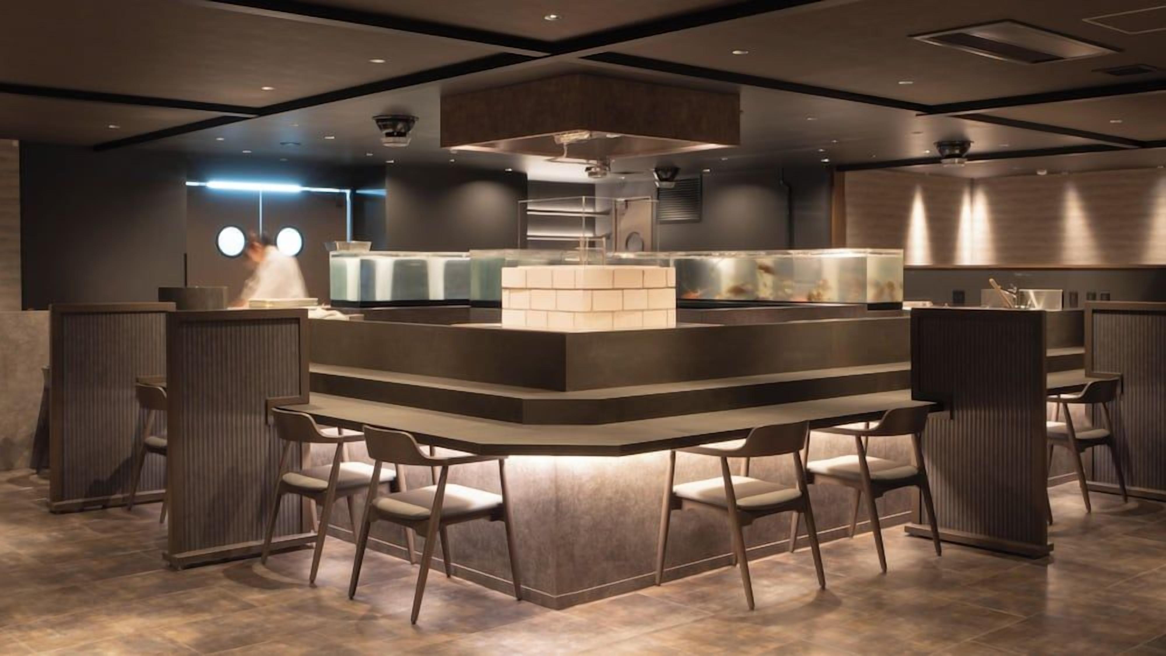 A modern bar area with a central counter, seating, and a visible kitchen in the background.