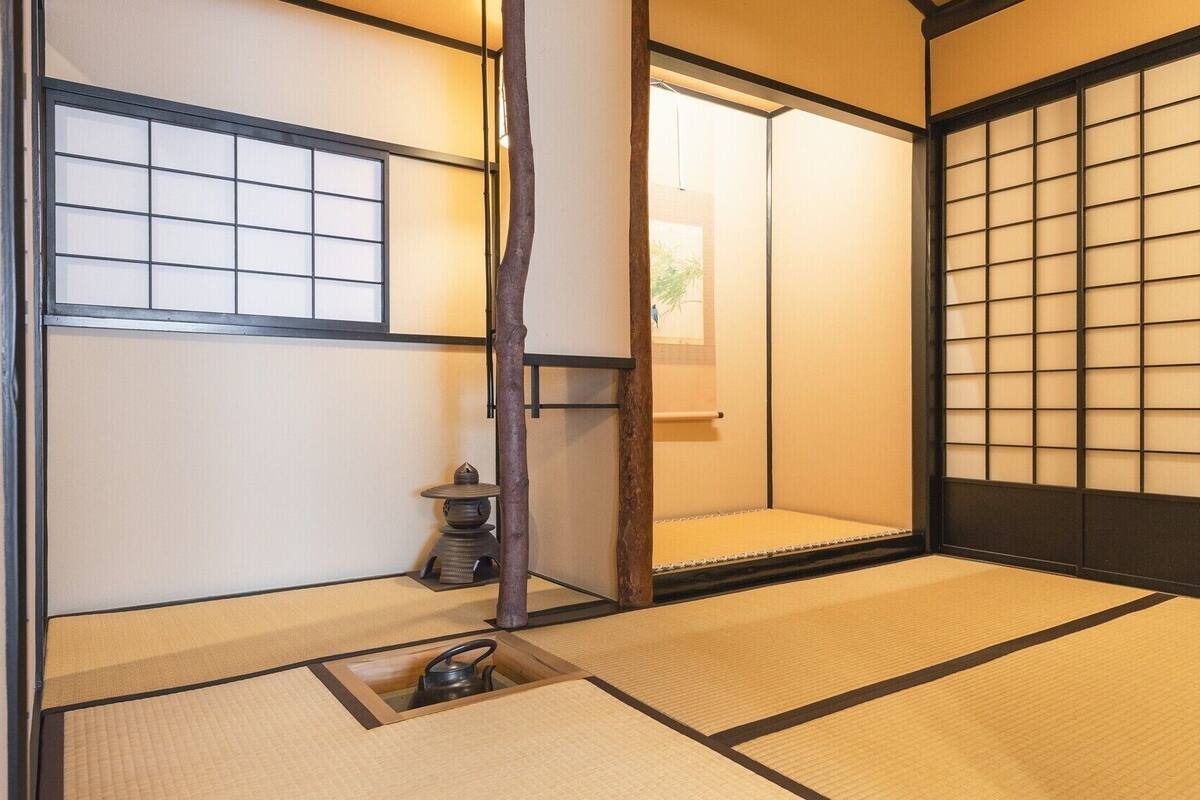 Ein traditioneller japanischer Raum mit Tatami-Boden, Shoji-Schirm und einem kleinen Tisch mit Wasserkocher.