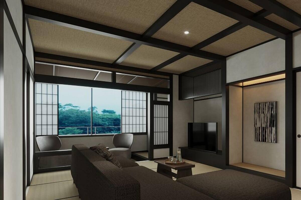 Ein modernes Wohnzimmer mit Sofa, Sesseln, Fernseher und einem großen Fenster mit Blick.
