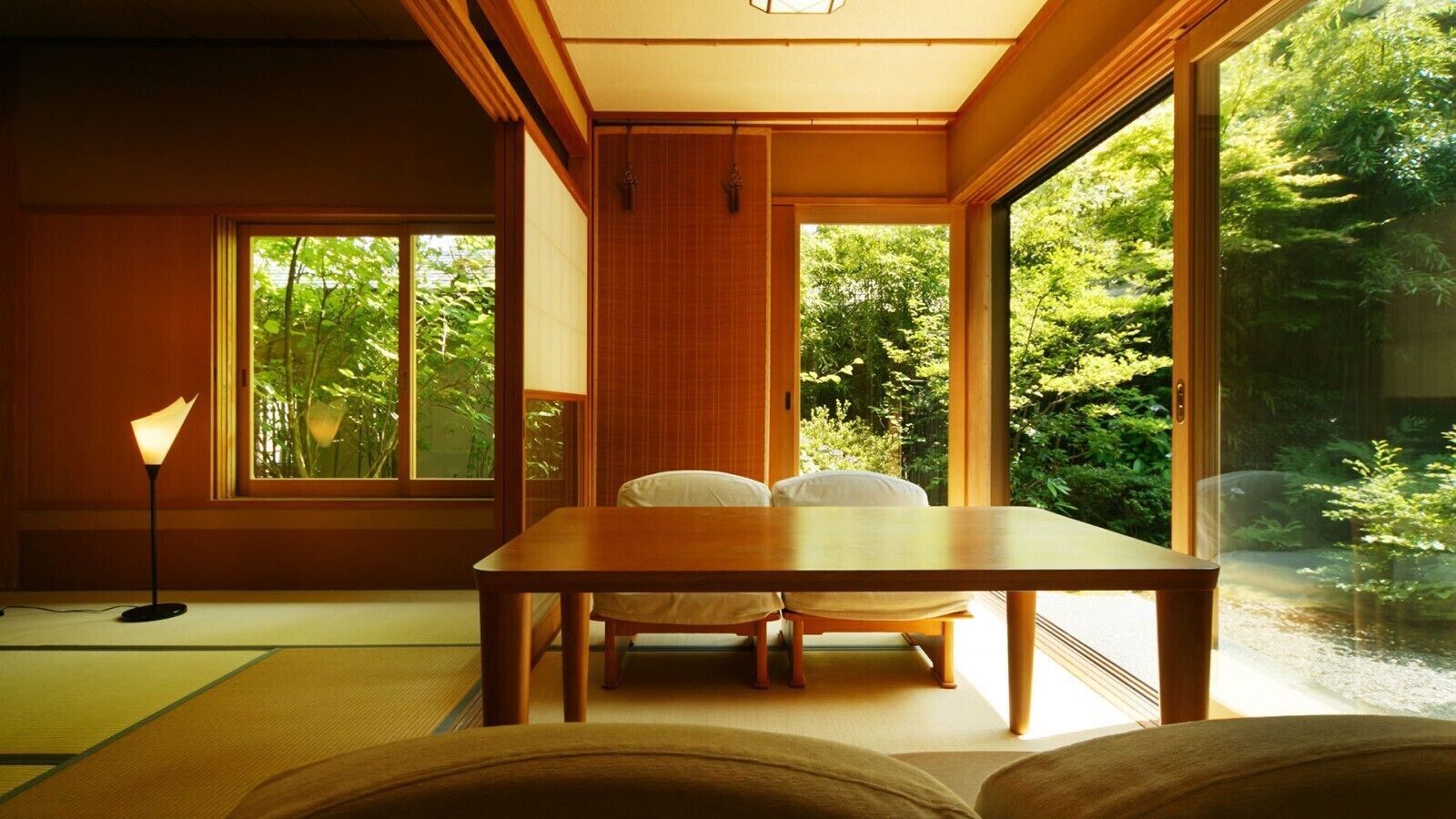 A traditional Japanese room with tatami flooring, a low table, and a sliding door leading to a garden.